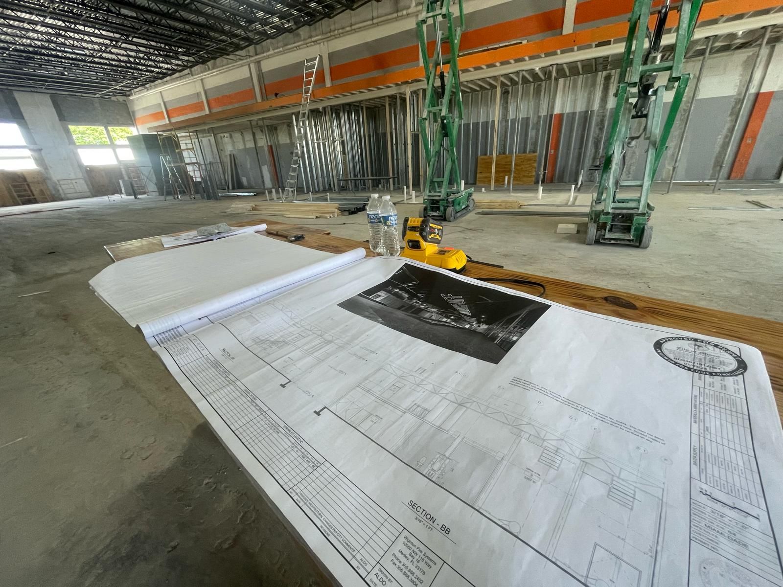 Commercial build out with approved drawings laid on the slab and scissor lifts in the space