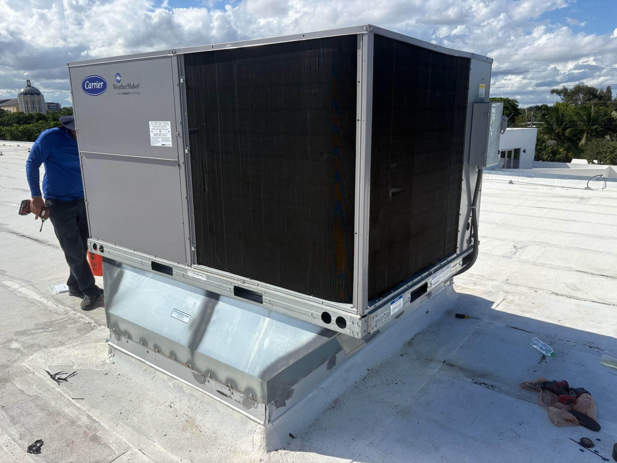 Carrier rooftop unit on a curb with a technician beside it