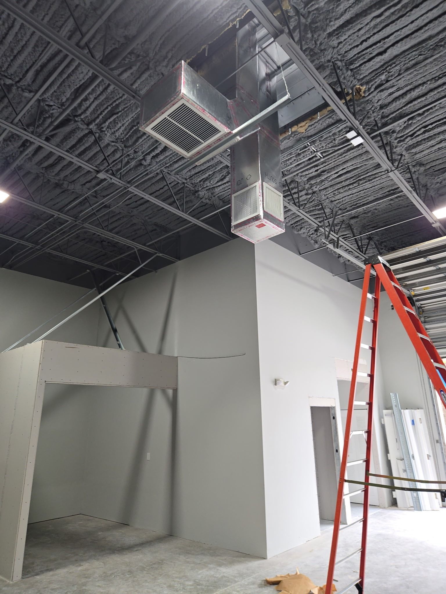 Supply duct drop from an open ceiling in a finished commercial space