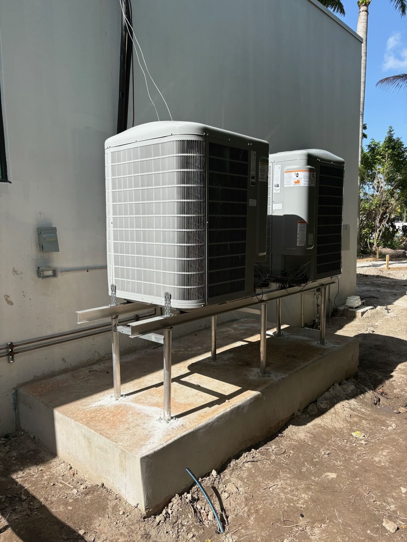 Two condensers on a raised steel stand beside a building