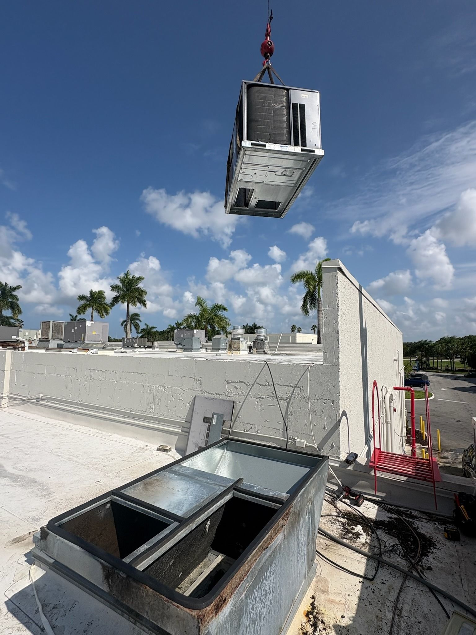 Crane lifting a rooftop unit over a commercial roof, Next Level Air Conditioning job in west Boca, 2026