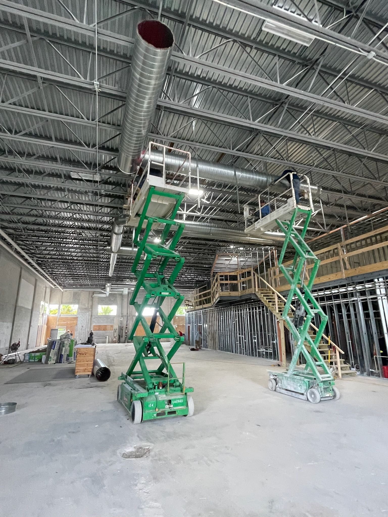 Crew on scissor lifts hanging spiral duct in a warehouse build-out