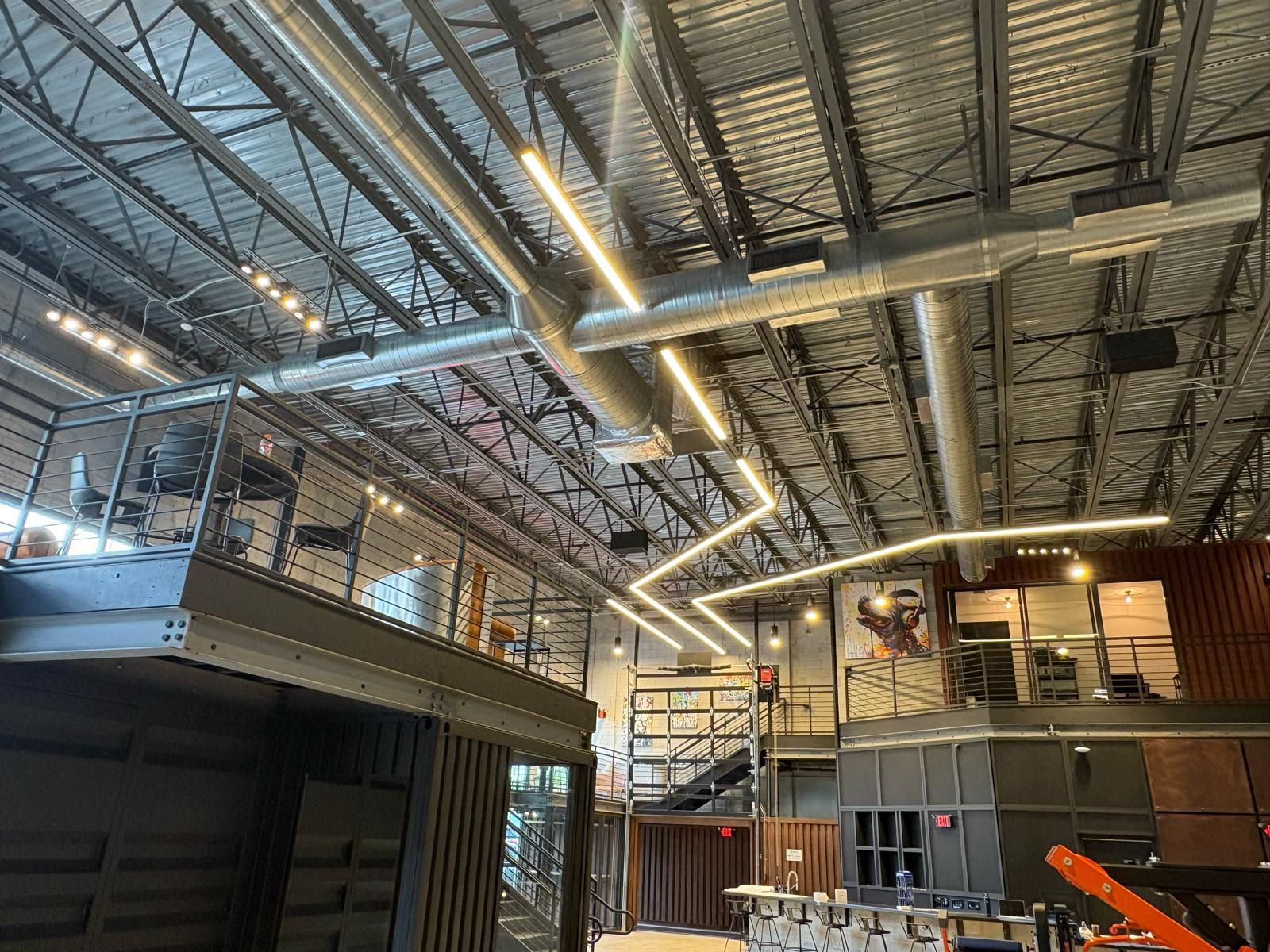 Commercial interior with exposed spiral duct over a container mezzanine and string lighting