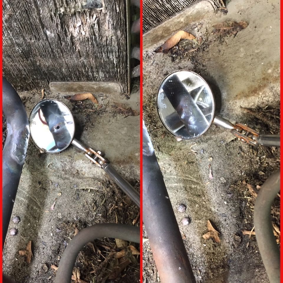 Inspection mirror held under a unit to show the pan and coil underside during a service call