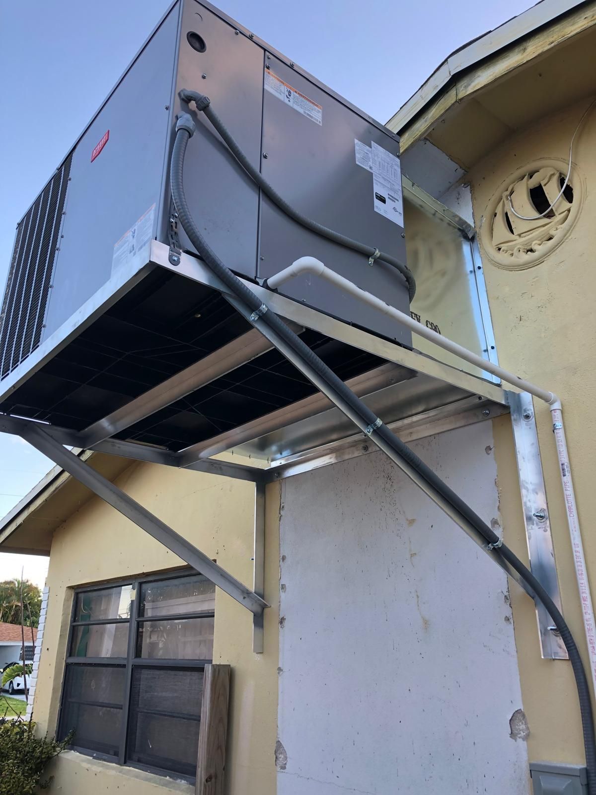 Packaged unit elevated on a fabricated wall bracket beside a window