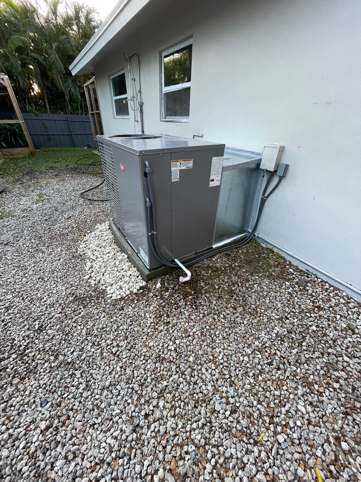 Packaged unit in a gravel side yard beside a home