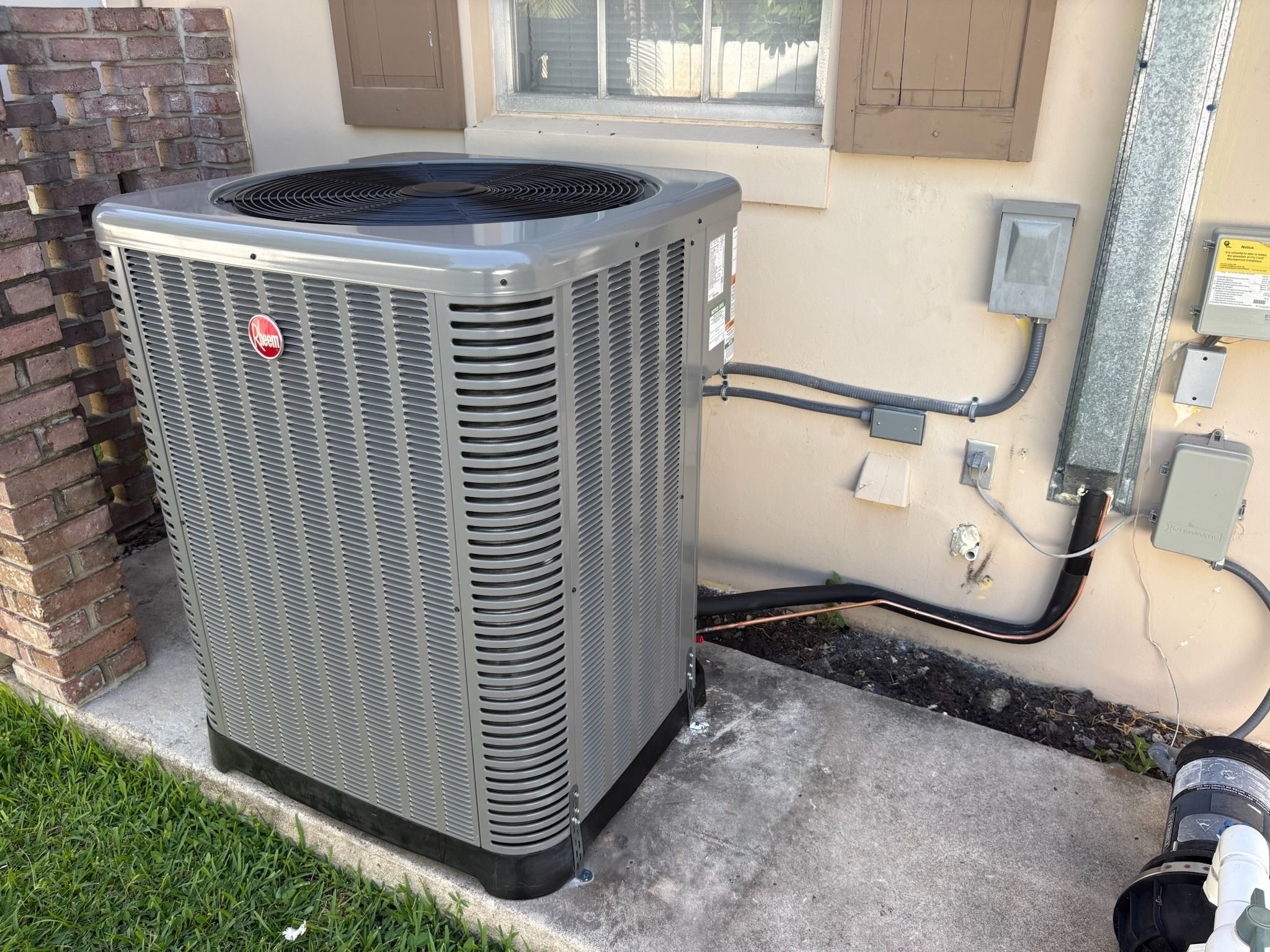 Rheem condenser on a pad beside a stucco home