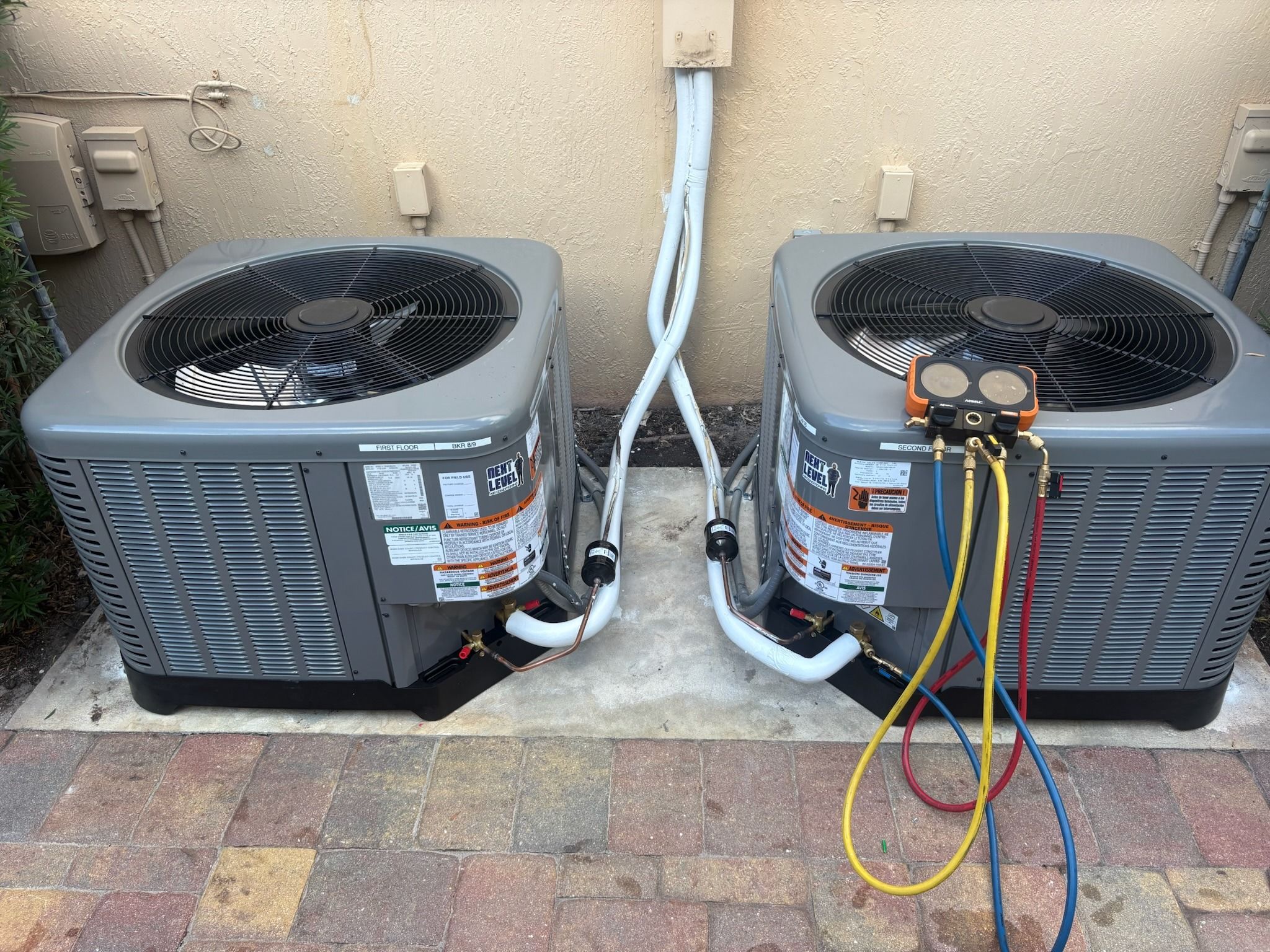 Pair of Rheem condensers on a paver pad with gauges connected, Next Level Air Conditioning job in Lake Worth, 2026