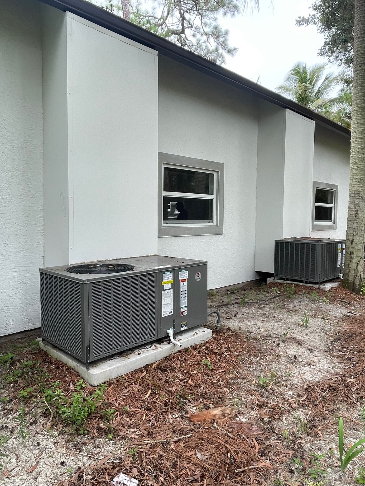 Two packaged units on pads beside a white stucco home, Next Level Air Conditioning job in Loxahatchee Groves, 2023