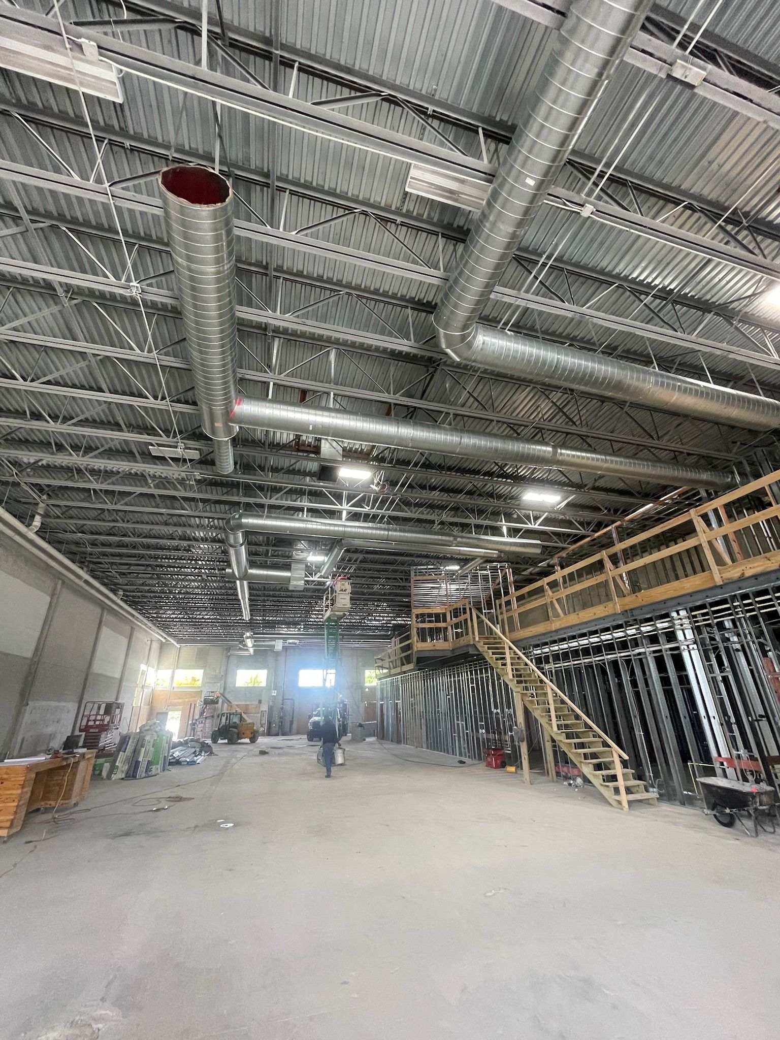 Warehouse build-out with exposed spiral duct running the length of the ceiling and a new mezzanine